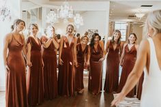 a group of women standing next to each other in front of a chandelier