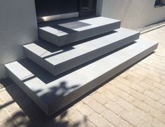 three concrete steps on the side of a building with shadows coming in from behind them