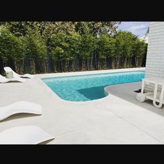 an empty swimming pool with lounge chairs around it