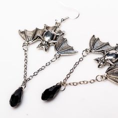 Unleash your inner darkness with these captivating Bat Earrings. Crafted from durable zinc alloy with a striking black finish, each earring measures 1.5 by 1 inch, featuring an elegant 1-inch chain adorned with a black diamond-shaped accent. Perfect for adding a touch of gothic charm to any outfit, these earrings are a must-have for your collection. Punk Alloy Jewelry For Halloween, Silver Alloy Crystal Earrings, Silver Alloy Earrings For Evening, Black Stainless Steel Jewelry With Black Enamel, Black Alloy Halloween Jewelry, Black Alloy Jewelry For Halloween, Formal Black Enamel Dangle Jewelry, Dangle Crystal Alloy Earrings, Black Enamel Dangle Jewelry For Formal Occasions