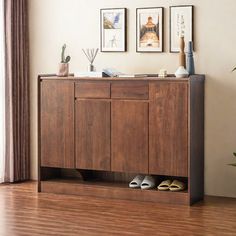 a wooden cabinet sitting on top of a hard wood floor next to a potted plant