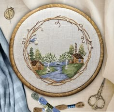 the embroidery kit is next to scissors and other crafting supplies on a tablecloth