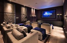 a home theater with couches and chairs in front of a large screen tv on the wall