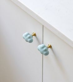 two blue and gold door knobs on a white cabinet in a kitchen or dining room