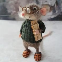 a toy mouse wearing a green sweater and striped slippers holding a piece of paper