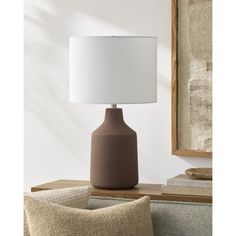 a brown table lamp sitting on top of a wooden table next to a white lampshade