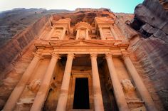 an ancient building built into the side of a mountain with columns and pillars in front of it