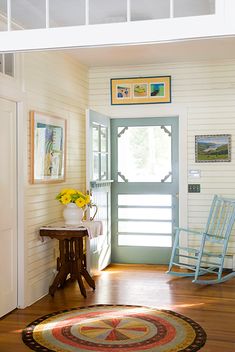 a blue rocking chair sitting next to a wooden table on top of a hard wood floor