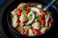 a bowl filled with chicken and peppers on top of a stove burner next to a spoon