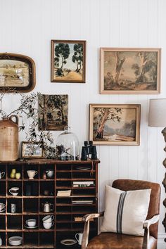 a living room filled with furniture and pictures on the wall next to a table topped with vases