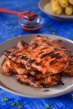 grilled chicken and potatoes on a white plate with blue table cloth next to it