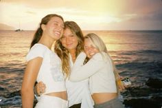 three girls hugging each other on the beach