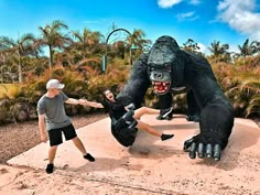 two people standing in front of a giant gorilla statue with one person on it's back