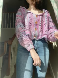 a woman in jeans and a pink sweater is standing on the stairs with her hands behind her back