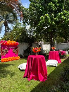 an outdoor area with tables and chairs covered in pink cloths, surrounded by palm trees