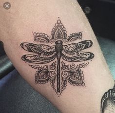 a black and white photo of a dragonfly tattoo on someone's left leg