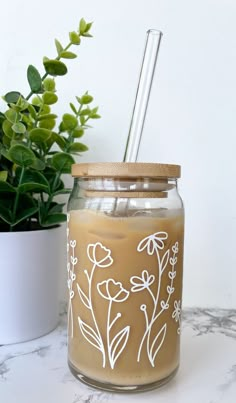 a jar with a straw in it sitting next to a potted plant