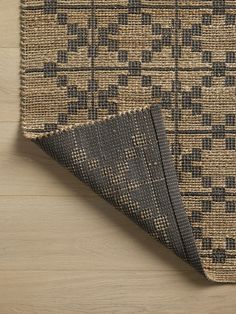 a close up of a rug on a wooden floor with a black and tan pattern