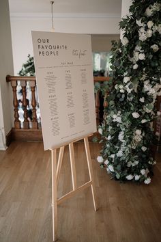 a sign that is on top of a wooden easel in front of a bunch of flowers