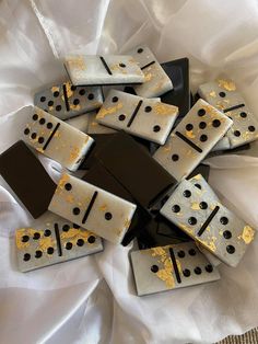 black and white dominos with gold spots on them sitting on a white table cloth