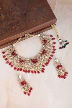 Red necklace featuring diamond carved cutwork, kundan embellishments, and bead drops. Paired with matching earrings adorned with similar designs. Red Kundan Necklace With Cutdana In Temple Jewelry Style, Festive Red Kundan Necklace With Zari Work, Red Zari Work Necklace For Diwali, Diwali Designer Jewelry With Zari Work, Red Intricate Design Temple Necklace For Festive Occasions, Designer Zari Work Jewelry For Diwali, Red Kundan Necklace With Cutdana In Temple Style, Red Kundan Necklace With Zari Work, Red Temple Jewelry Necklaces With Zari Work