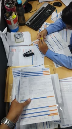 two people sitting at a desk working on papers