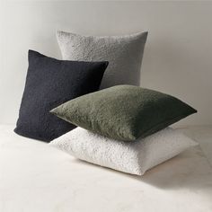 three pillows stacked on top of each other in different colors and sizes, one black, one white