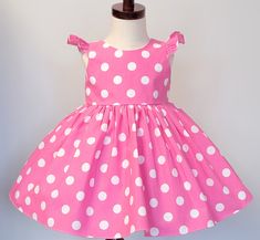 Display dress is a size 3t shown on a size 3t mannequin and includes a petticoat slip under which is NOT INCLUDED in purchase of dress This fun polka dot dress features large white polka dots on a bright pink background. It would be perfect for a Minnie Mouse themed birthday party or for any little one that loves polka dots!  Dress is available in sizes 9-12 months- size 8 girls. If you would like a size that isn't listed, please feel free to contact me so I can accommodate requests.  The bodice has a boat neck and the back is scooped. It is lined with soft cotton and it snaps in the back with Kam snaps for easy on and off. (Kam snap colors may vary depending on current stock). There are matching fabric tie backs that tie into a bow in the back of the dress for a perfect fit around the wai Cute Dresses For Party, Minnie Mouse Dress, Pink Polka Dot Dress, Special Dresses, Dress Gift, Pink Polka Dots, Dot Dress, Hem Dress, Polka Dot Dress