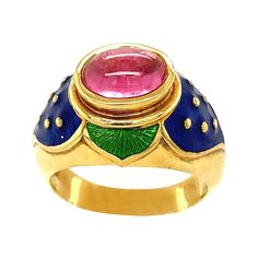 Lovely 18 karat yellow gold ring designed with the intention of a flower. The ring centers an oval cabochon pink tourmaline set horizontally. Green and blue enamel accent the center stone. Ring size 7.5 Stamped Cellini 750 Luxury Ceremonial Hallmarked Enamel Ring, Luxury Yellow Gold Enamel Ring With Cabochon, Unique Yellow Gold Enamel Ring For Formal Occasions, Formal Yellow Gold Cabochon Sapphire Ring, Unique Cabochon Ruby Ring For Formal Occasions, Formal Yellow Gold Cabochons With Bezel Setting, Unique Yellow Gold Enamel Ring For Anniversary, Unique Gold Enamel Ring For Formal Occasions, Heirloom Yellow Gold Emerald Cabochon Ring