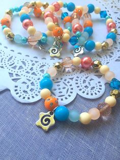 an assortment of colorful beads and charms on a lace doily next to a white doily