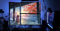 a computer desk with two monitors and a keyboard in front of the monitor is an image of a woman sitting under a tree