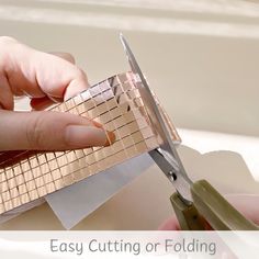 a person cutting paper with scissors on top of some pieces of metal sheeting material