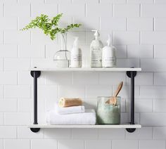 two shelves with towels, soaps and other items on them in front of a white brick wall