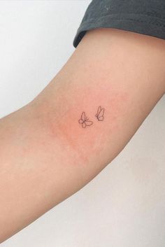 a woman's arm with two small butterflies on the left side of her arm