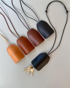 three different colored leather purses on a white surface with two keys attached to them