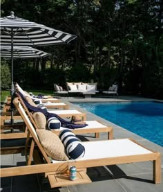 a row of lounge chairs sitting next to a swimming pool with an umbrella over it