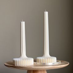 two white candles sitting on top of a wooden tray