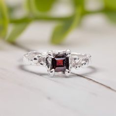 Elevate your love with this stunning Red Garnet ring - a unique blend of artistry and timeless elegance. Handcrafted in wax and cast in solid Sterling Silver, its organic textured band exudes natural charm. This one of a kind engagement ring features a stunning square red crystal as the January birthstone - in celebration of love's eternal bond. T H E ∙ S M A L L ∙  D E T A I L S * Square cut Red Garnet (5 x 5mm) * Sterling Silver textured band M A T E R I A L ∙ O P T I O N S * Sterling Silver * Red Crystal Ring, January Birthstone Rings, Garnet Engagement Ring, Red Garnet Ring, Unique Engagement Ring, Garnet Ring, Alternative Engagement Rings, January Birthstone, Crystal Ring