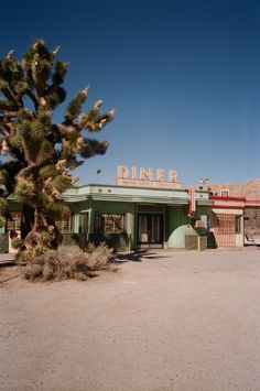 a small green building sitting in the middle of a desert