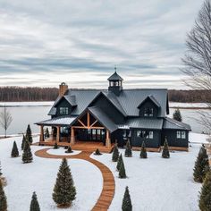 a large house surrounded by snow covered trees in the middle of a lake with a wooden walkway leading to it