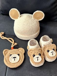 a crocheted teddy bear hat, slippers and booties are sitting on a couch