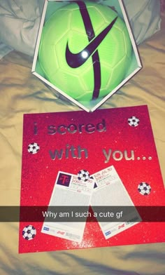 a soccer ball sitting on top of a bed next to a sign that says i scored with you