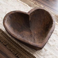 a wooden heart shaped bowl sitting on top of a table