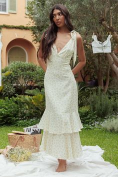 a woman in a white dress is standing on a blanket and looking at the camera