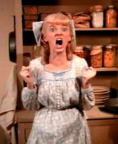 a woman with her mouth wide open standing in front of some shelves