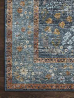 an area rug with blue and orange flowers on the side, in front of a wooden floor