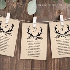 wedding seating cards with antlers on them hanging from a clothes line and eucalyptus leaves