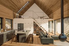 a large open concept living room and kitchen area with wood flooring, stairs leading up to the second floor