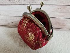 a small red purse sitting on top of a white table next to a wooden wall