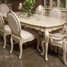 a dining room table with white chairs around it